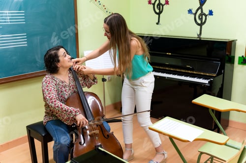 Preview: Music teacher helping student playing cello in classroom