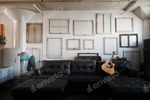 Preview: A wall hung with reversed picture frames. A man at an open fridge door leaning in.