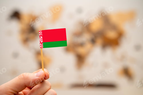 Preview: Belarus flag in mans hand on the world map background.