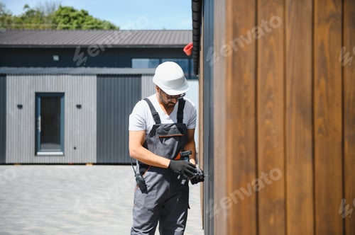 Preview: Construction worker assembling prefabricated modular house using power tool