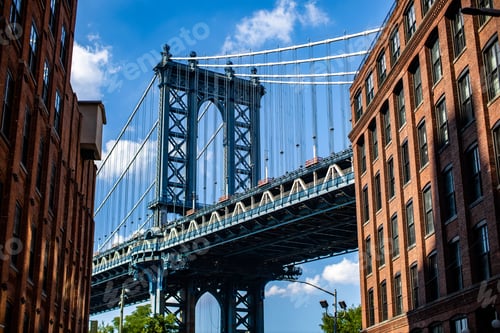 Preview: Beautiful low angle shot of the Manhattan Bridge in New York City under a bright blue cloudy sky