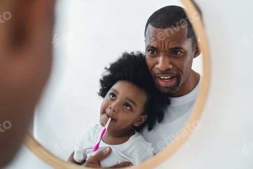Preview: African American father little son spend time together have fun brushing teeth together look mirror.