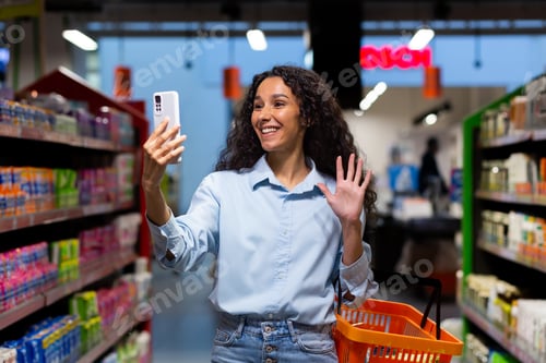 Preview: Shopping. A young Latin American woman walks in a supermarket between rows of shelves with a