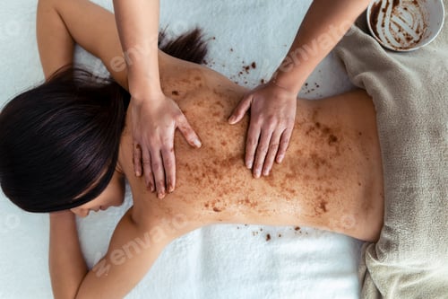 Preview: woman applying chocolate cream for body treatment to a pretty woman on the spa center.