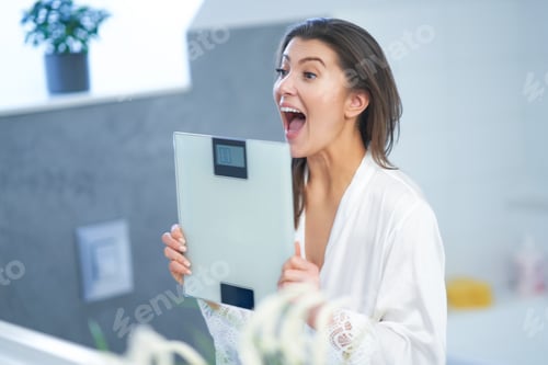 Preview: Young nice brunette woman in the bathroom with weight scale