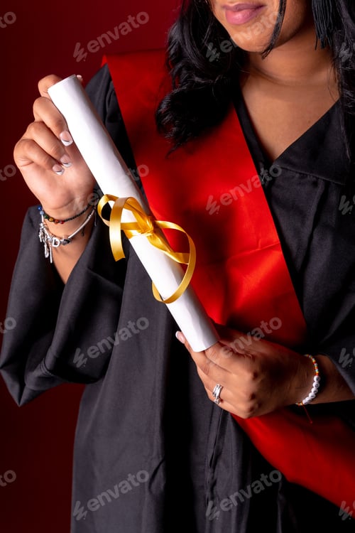 Preview: Young female graduate standing proudly in her academic regalia with her diploma