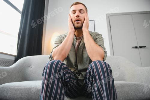Preview: Ill man sitting on his bed with his head on his hand