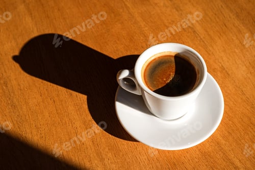 Preview: A cup of black coffee on the table in the sunlight