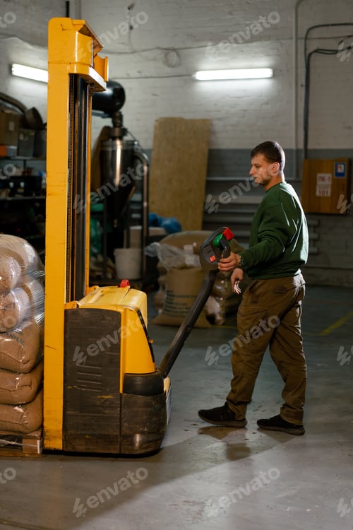 Preview: a worker at coffee factory uses a yellow forklift to lower bags of coffee