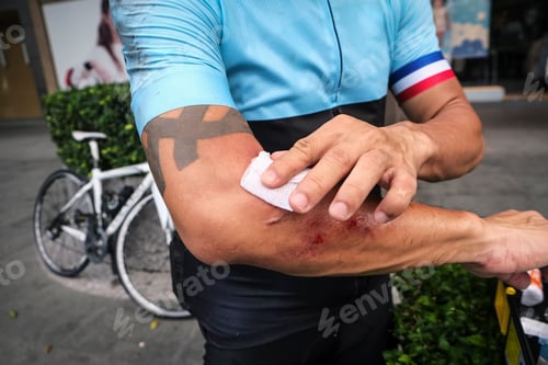 Preview: Close-up of a cyclist bandaging his wounds after falling from sport bicycle