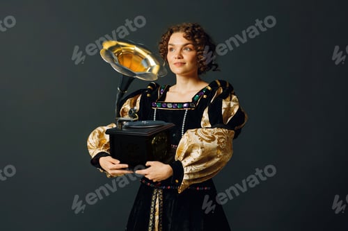 Preview: Portrait of a young woman dressed in a medieval dress holding a gramophone listens classical music.