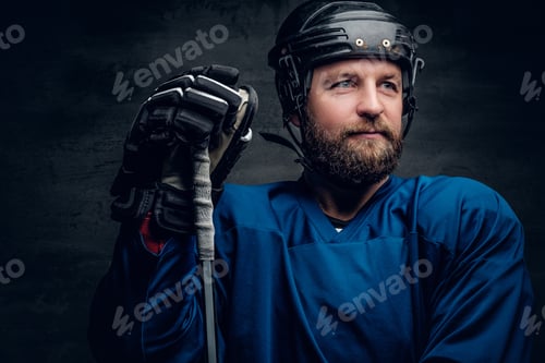 Preview: A bearded ice-hockey player in safety helmet holds the gaming st