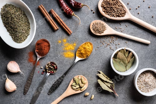 Preview: top view of various aromatic dried spices in bowls and spoons on grey surface