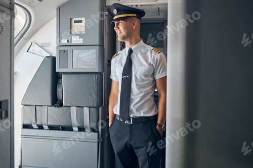 Preview: Handsome male captain standing inside commercial airplane