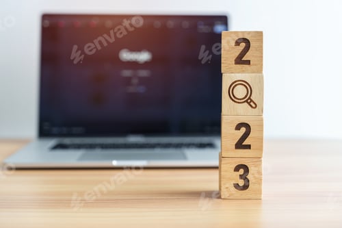 Preview: 2023 block with magnifying glass icon against laptop background.