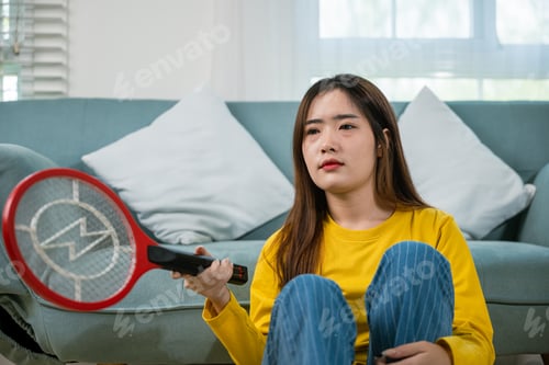 Preview: Asian female sitting floor using mosquito device swatter or electric net racket