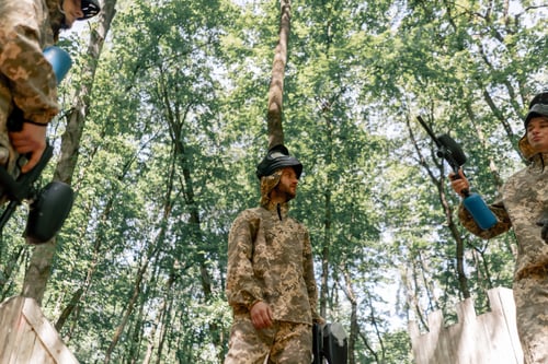 Preview: in the forest in middle of the field pintball players discuss and gesticulate how to play the game