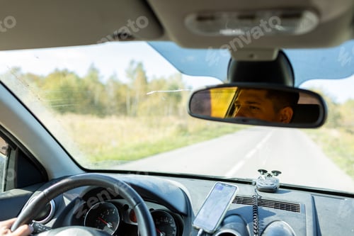 Preview: A man in a car checks the road using a navigator from a mobile phone