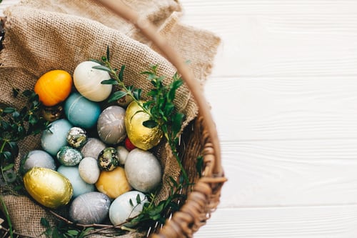 Preview: Stylish easter eggs in rustic basket on white wooden background