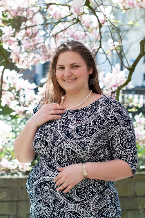 Preview: Portrait of a beautiful plump caucasian confident woman in magnolia flowers