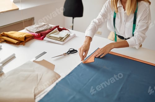 Preview: Dressmaker measures cloth at workplace in workshop
