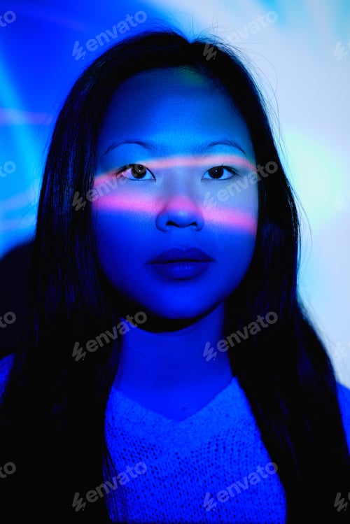 Preview: Attractive Asian woman in dark room with neon illumination