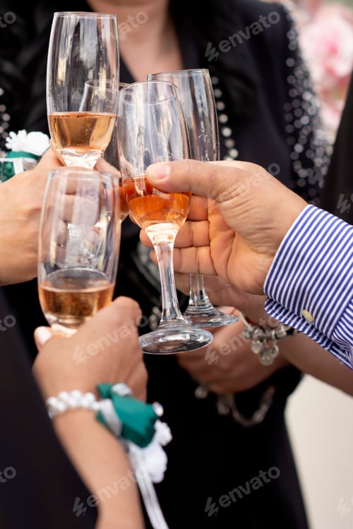 Visualização: Mãos com taças cheias de champanhe as conectam com o tilintar de uma festa alegre.