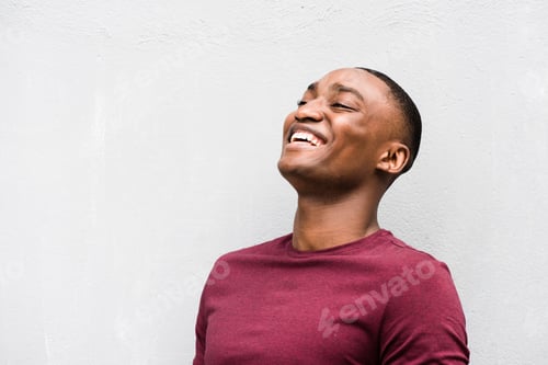 Preview: Close up happy young African American man laughing by gray background