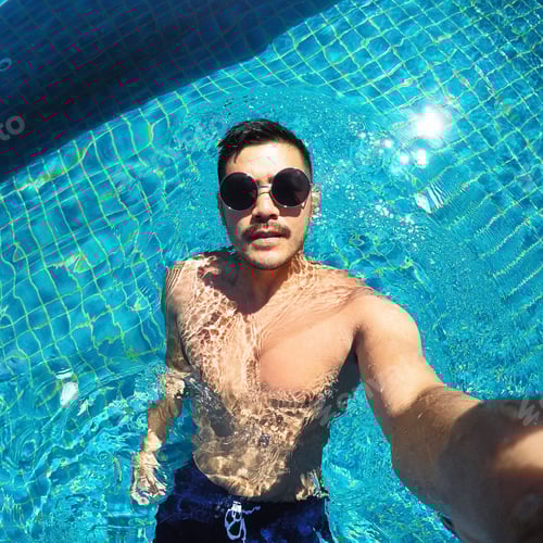 Preview: Young man swimming in pool taking a selfie