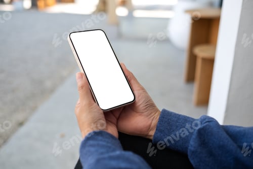 Preview: Mockup image of a woman holding and using mobile phone in the outdoors