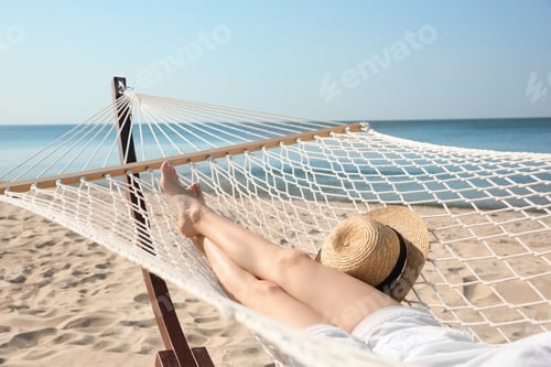 Preview: Young woman relaxing in hammock on beach