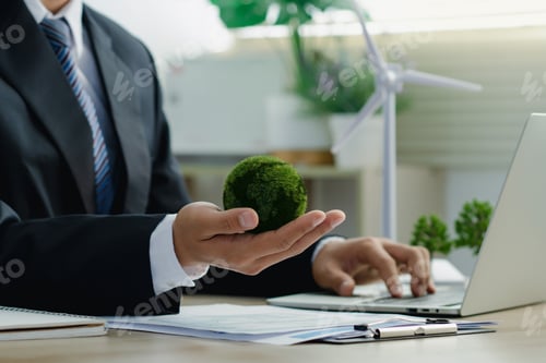 Preview: Green Earth in businessman hands and wind turbine model for Protecting Planet.Green business.