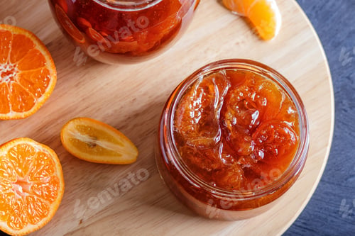 Preview: Tangerine and kumquat jam in a glass jar on a black wooden background.