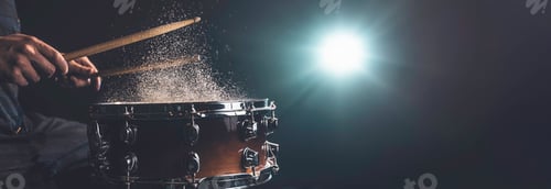 Preview: Drummer using drum sticks hitting snare drum with splashing water.