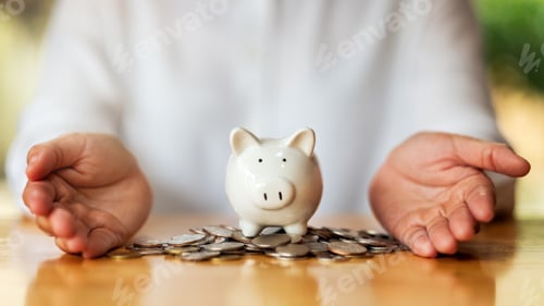 Preview: Closeup image of a woman's hands showing piggy bank and coins on the table for saving money concept