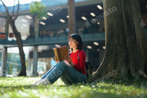 Preview: Smiling Woman Reading Book Outdoors on Sunny Day