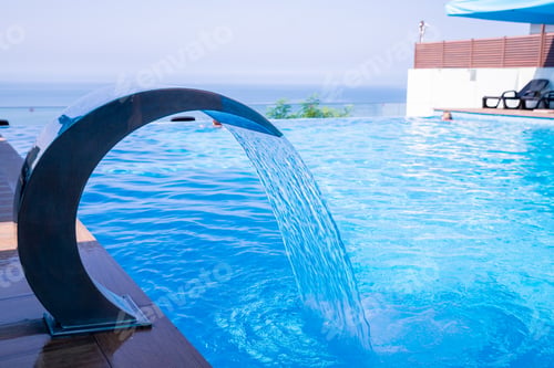 Preview: Empty Swimming pool with waterfall jet and jacuzzi in action.Hydrotherapy waterfall. summer sunny