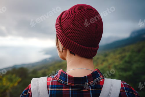 Preview: Stylish hipster woman with hat walking on top of mountains.