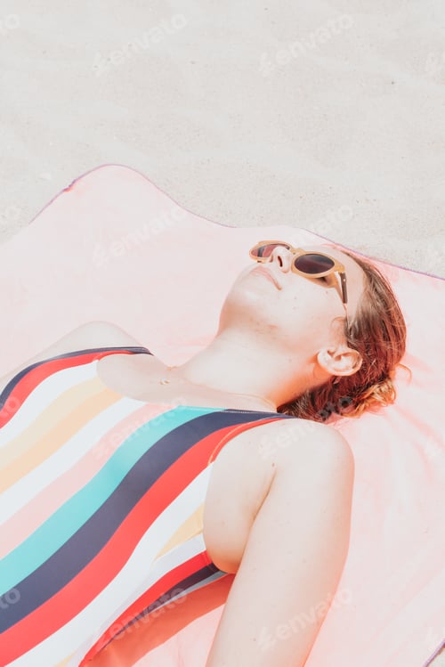 Preview: Image from above of a young woman in a colorful swimsuit taking a sunbath