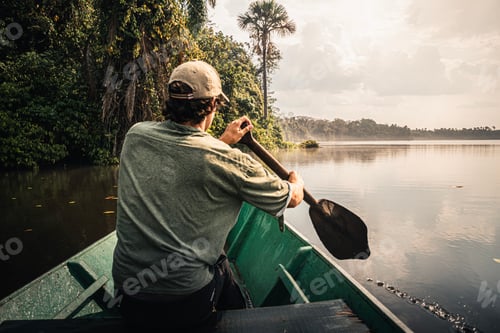 Preview: Explorer paddling a canoe on the amazon river at sunset