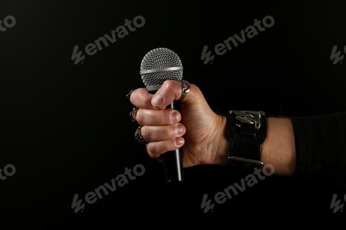 Preview: Man hand with microphone isolated on black