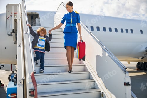 Preview: Helpful airline hostess assisting a kid in exiting an aircraft