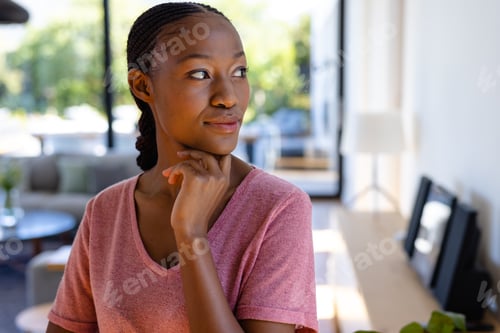 Preview: Happy african american woman looking away and smiling in sunny living room
