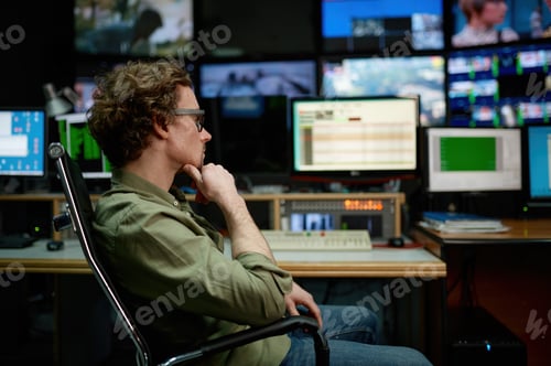 Preview: System administrator sitting in chair looking at computer screen in server room
