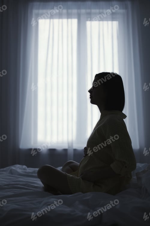 Preview: Beautiful pregnant woman sitting on bed at home