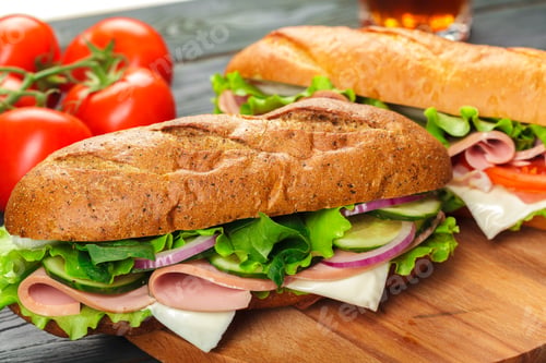 Preview: Fresh sandwich with lettuce, meat, and vegetables on a wooden board next to ripe tomatoes