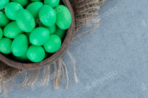 Preview: Green candies in the cup on the trivet, on the marble background