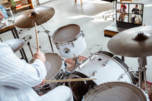 Preview: Close up of caucasian musician playing drumms during online concert with the band at home isolated