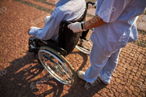 Preview: Nurse in uniform taking care of disabled patient in wheelchair