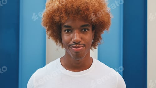 Preview: Close up, guy looks with smile at the camera on striped wall background